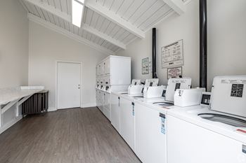 A laundry room with washers and dryers lined up.